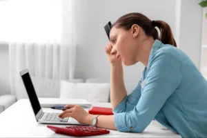 A woman looks worried while doing her budget, showing how knowing about different types of inflation could help navigate your finances more confidently.