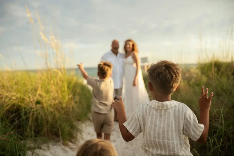 Couple discovering the fruit of goal-based financial stewardship, on vacation at a beach at sunset with their children after they saved up and prioritized what mattered most to them..