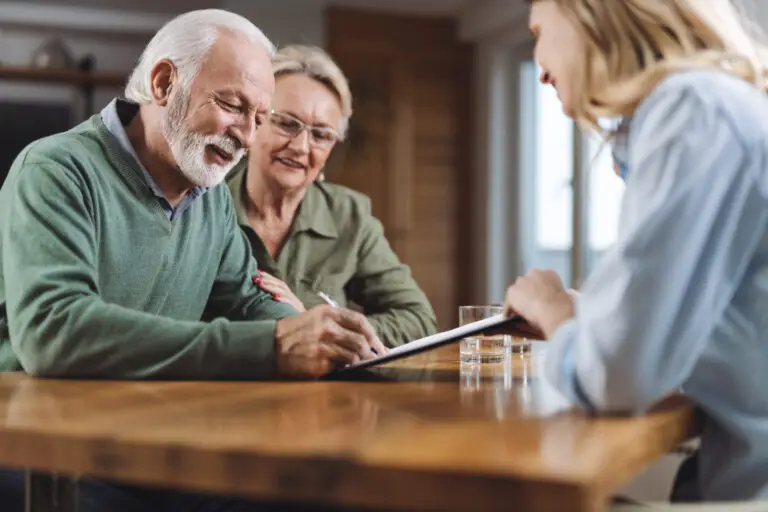 Elderly couple signing documents to create a SLAT trust with a qualified financial adviser