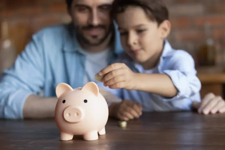 Father helping son put money into piggy bank to represent unused 529 funds