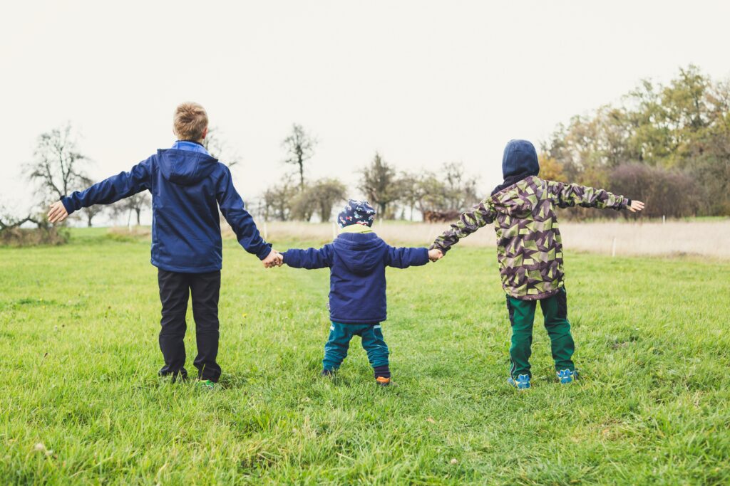 Siblings holding hands in a field to show how you can use unused 529 funds for sibling's educational expenses