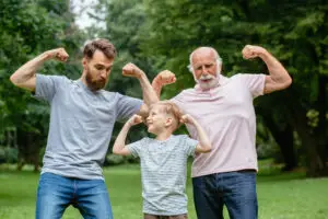 Grandpa, father and son smiling and showing their muscles to represent the idea of wealth management strategies that impact multiple generations