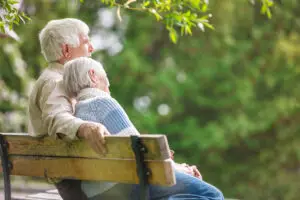 Elderly couple sitting on a bench and talking to one another about their new wealth plan