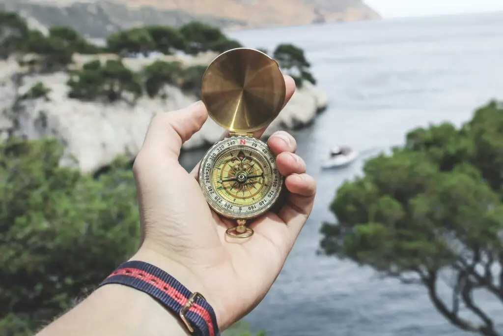 Person holding a compass next to a river, to represent the importance of incorporating purposeful direction in financial planning for attorneys