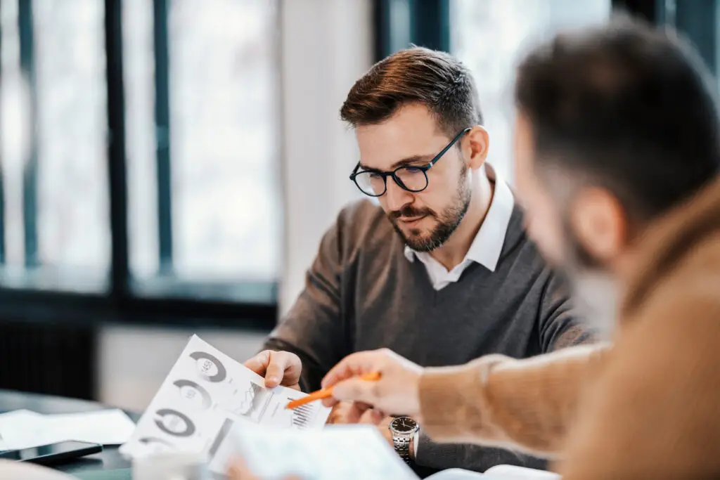 Two gentlemen sitting down at a table, looking at charts as they go through an annual financial review.