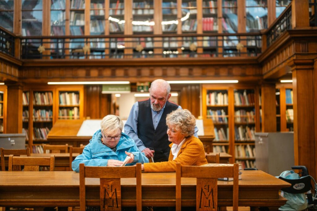Simple steps in financial planning for elderly parents include having a clear conversation, like the one the family pictured in this library are having.