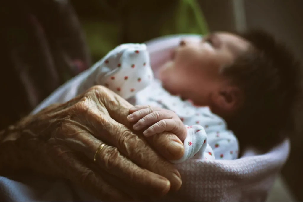 A grandmother taking in her beautiful new granddaughter and considering what the best investments for grandchildren are as she thinks of how she can give this new little one the best possible life that she can.