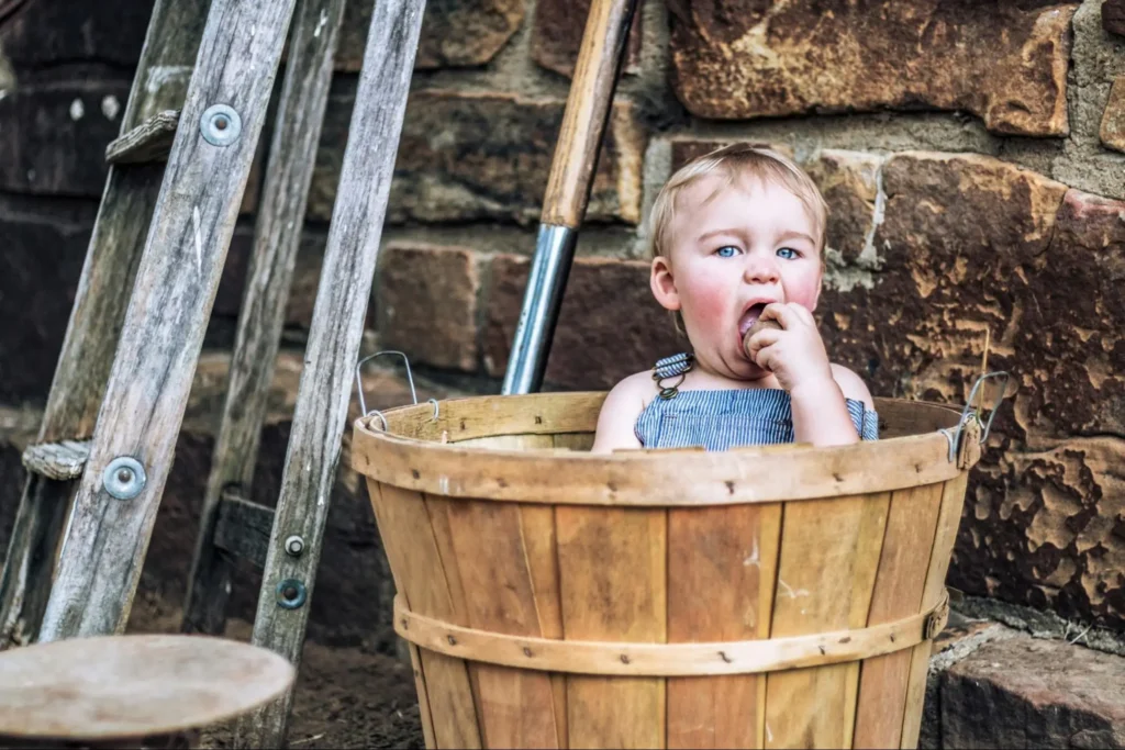 A little boy licks a potato on a farm, reminding us that long-term financial planning takes patient, quiet work much like a potato’s growth.