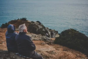A couple nearing retirement contemplates the impact of inflation on retirement income and how it could impact their future while looking at the sea.