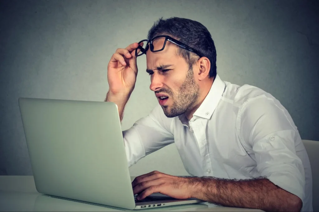 A man scrutinizing his computer screen represents the common confusion around cost pull inflation and other financial terms.