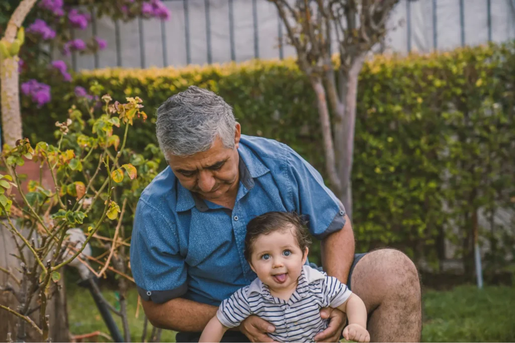 A grandfather holds his grandchild in the garden, illustrating why a financial advisor for pilots needs to understand a pilot’s life beyond his portfolio.