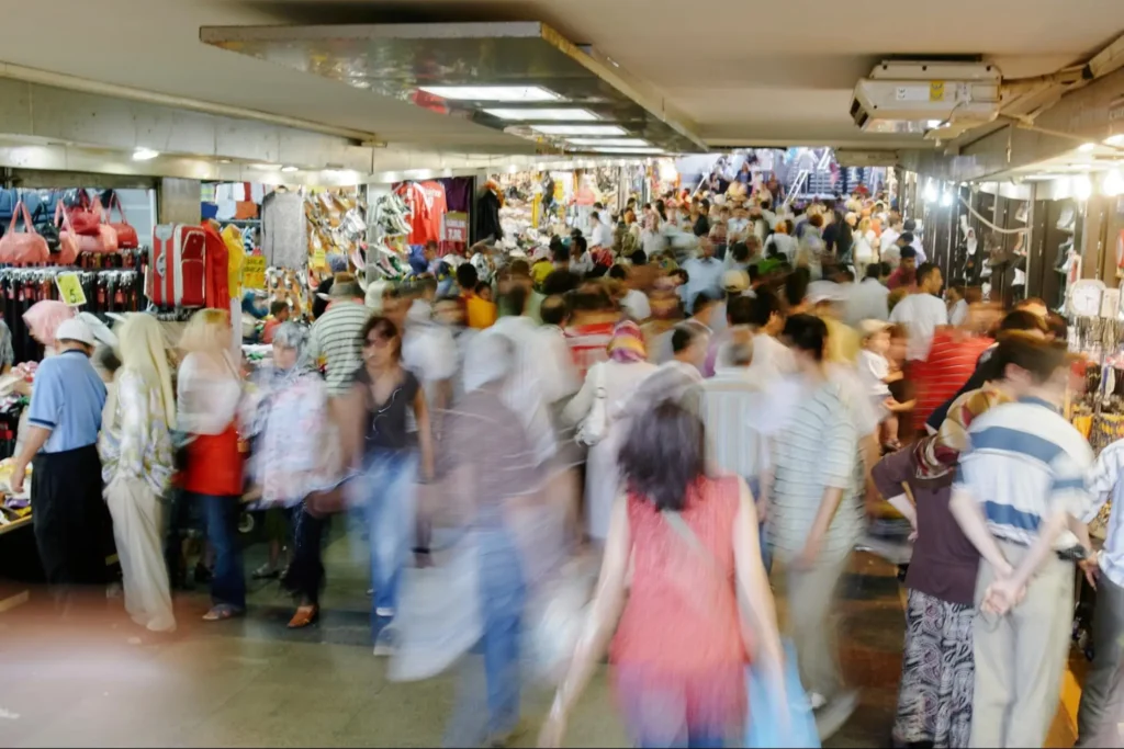A crowded shopping center represents demand outpacing supply in demand pull inflation.
